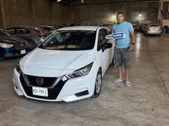 Cliente de EzRide junto a su Nissan Versa blanco recién entregado