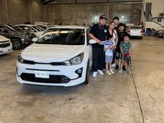 Familia numerosa recibiendo su Kia Rio blanco en la entrega de EzRide